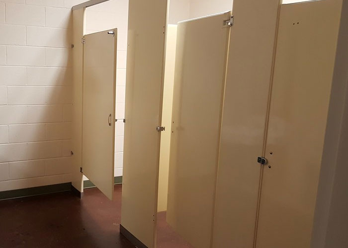 Public restroom stalls with some doors partially open, evoking disturbing things people saw and experienced while at work.