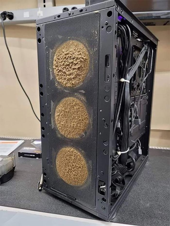 Dust-covered gaming PC with clogged fans in a cursed gaming setup, showing poor maintenance and airflow issues.