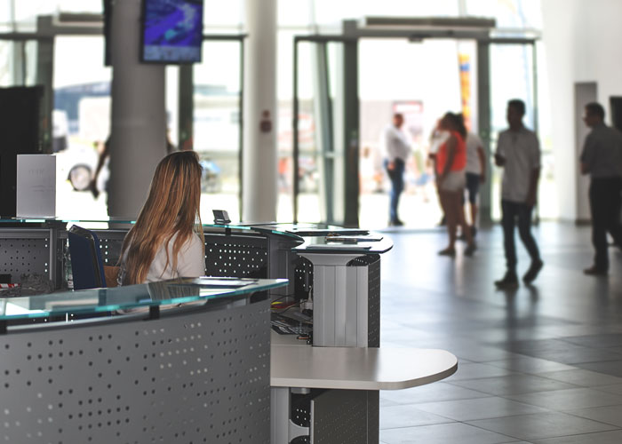 Woman sitting at a reception desk watching people in an office lobby, illustrating disturbing things people saw at work.