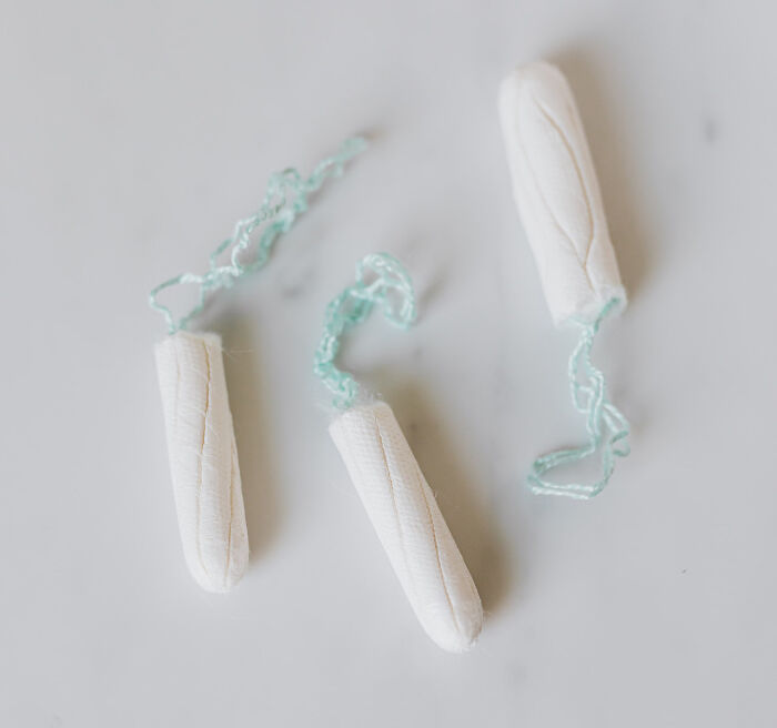 Three white tampons with blue strings on a plain surface representing brand and item choices never again
