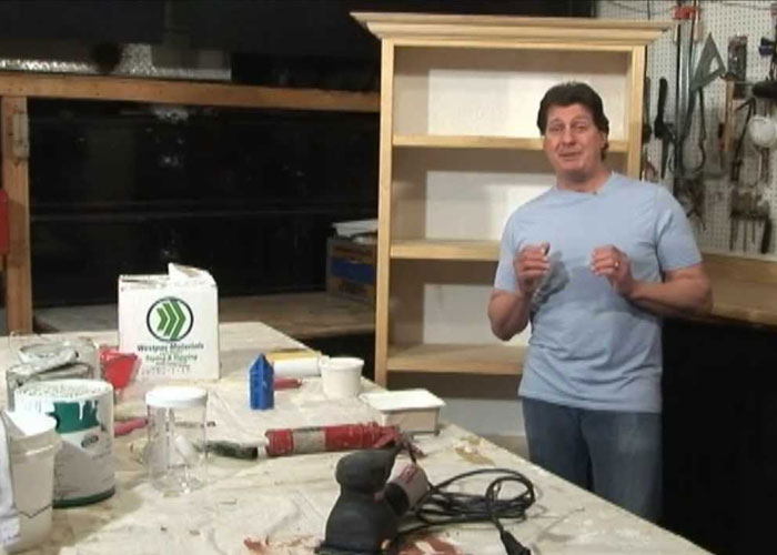 Man standing in workshop surrounded by tools and materials, sharing homeowning knowledge and tips.