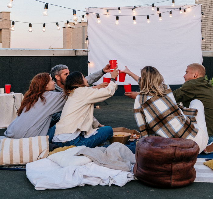 a group of people sitting on the roof and clapping plastics glasses