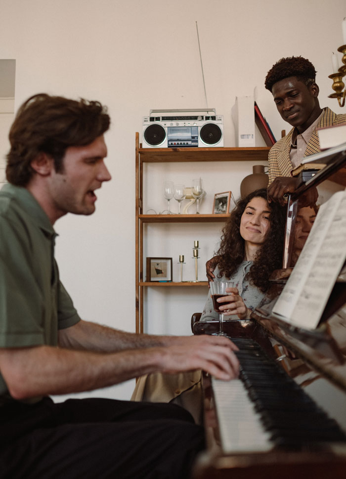 man playing the piano around his friends