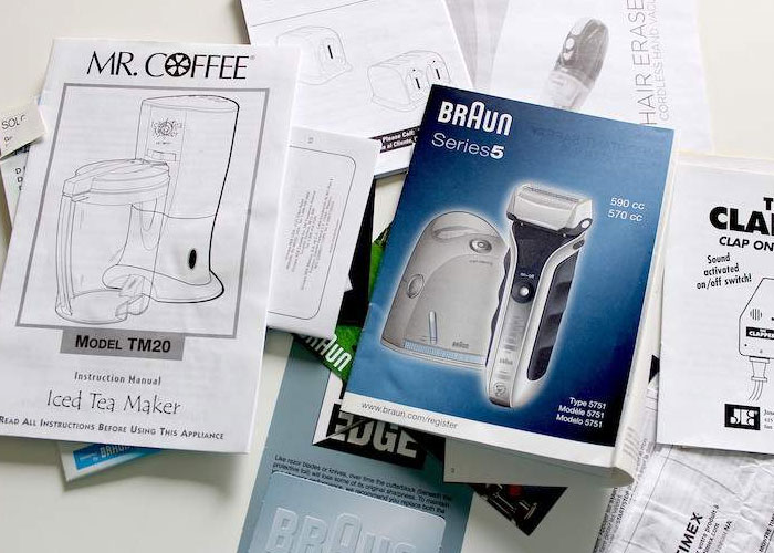 Instruction manuals and product guides spread out on a table, showing homeowning tips and device information.