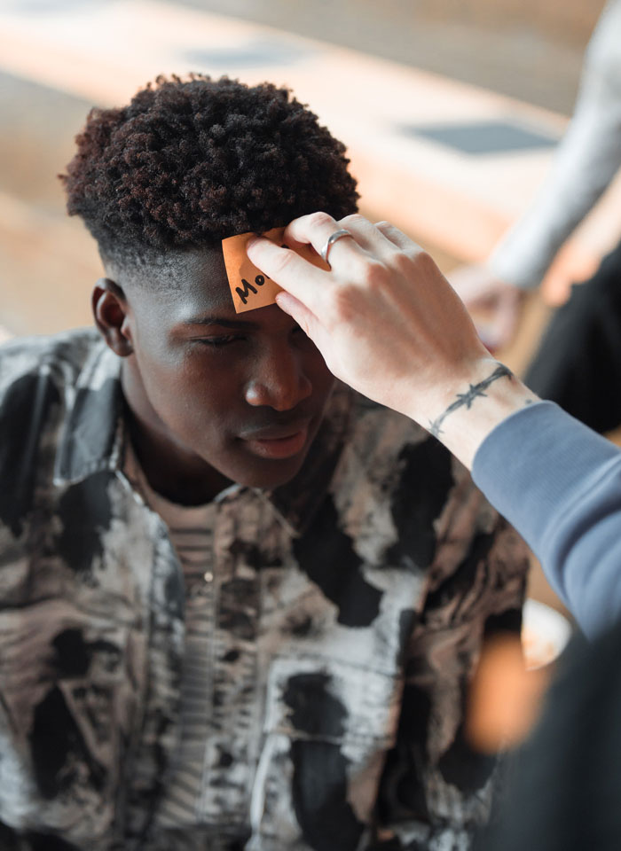 person sticking a sticker on the head of another person