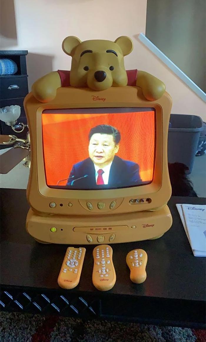 Retro cursed gaming setup featuring a Disney Winnie the Pooh TV and matching remotes on a black table.