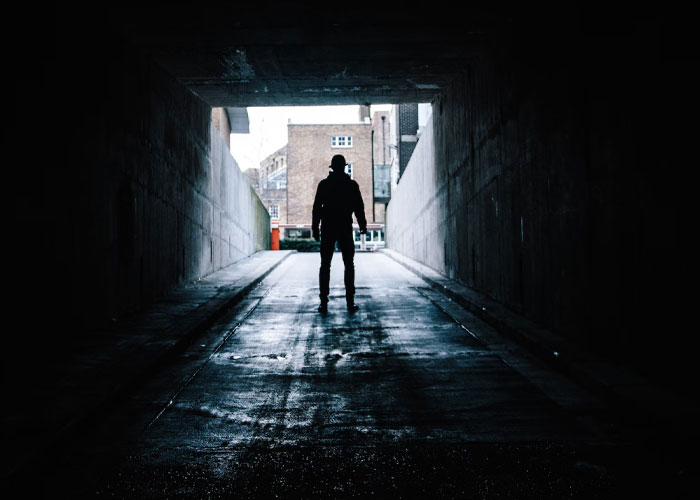 Silhouetted figure standing in a dark tunnel, evoking a disturbing scene experienced while at work.