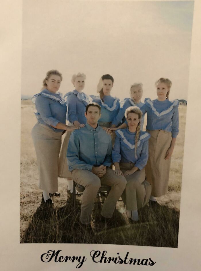 Group posing in blue and beige outfits for a funny Christmas card in a field with "Merry Christmas" text below.