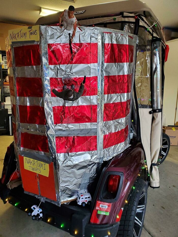 Christmas humor: a cart decorated as a skyscraper with a toy figure climbing, labeled "Nakatomi Towers" for festive amusement.
