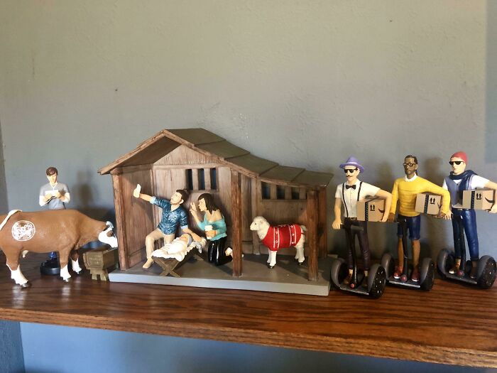 Humorous Christmas nativity scene with modern twist, featuring figurines on Segways and a cow with earbuds.