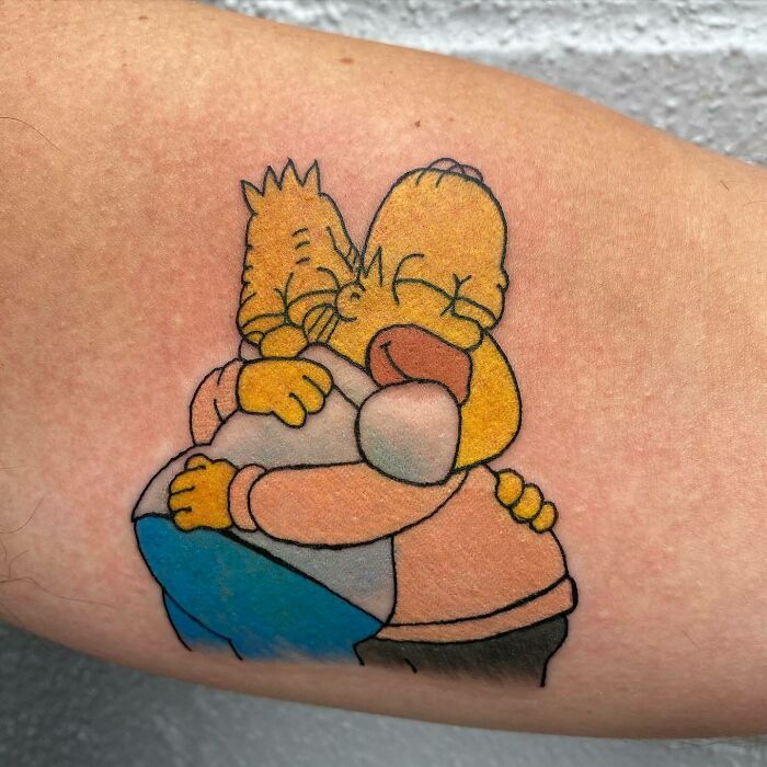 Cartoon tattoo of Homer hugging his dad, showcasing sweet nostalgia.