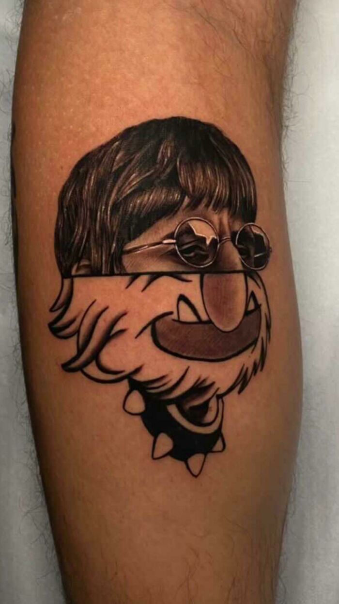 Cartoon tattoo of a character with sunglasses and a shaggy hairstyle on a person's calf.