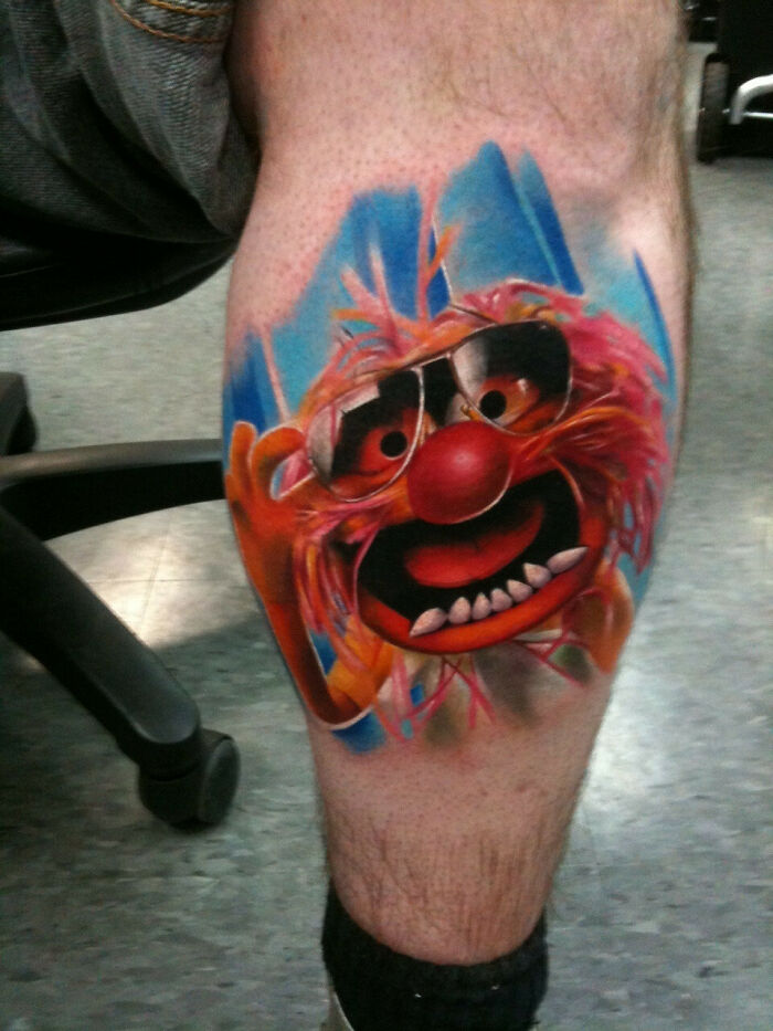 Cartoon tattoo of a colorful character on a person's leg, reflecting childhood favorites.