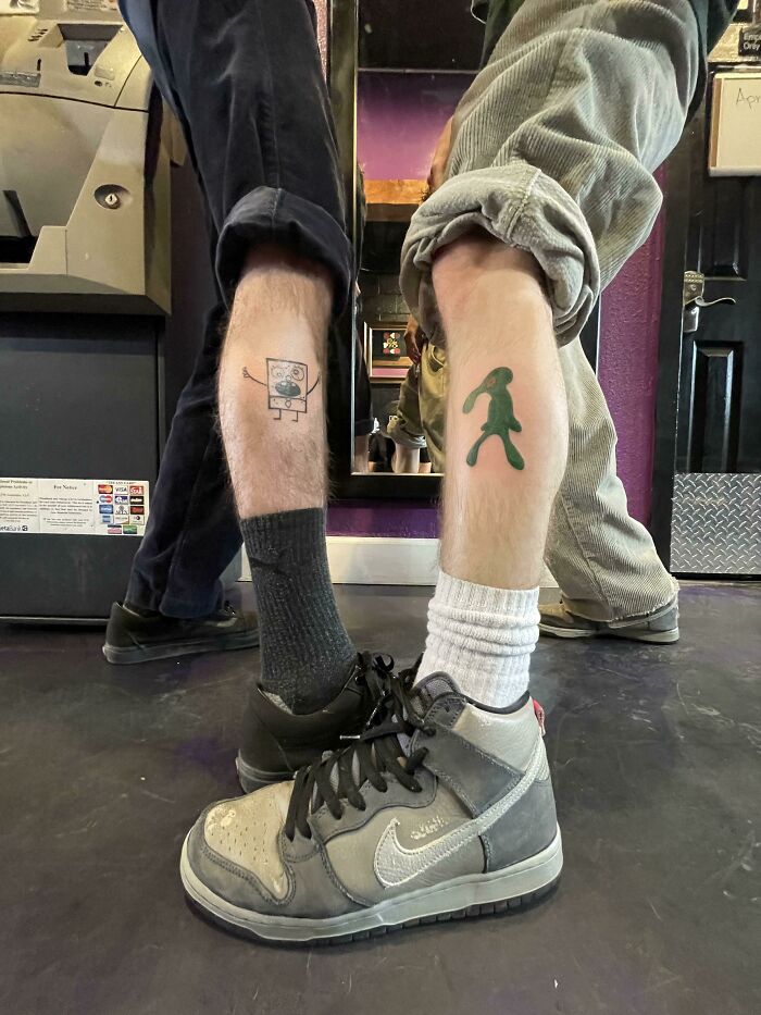 Two legs showing cartoon tattoos, with shoes visible, reflecting childhood favorites.
