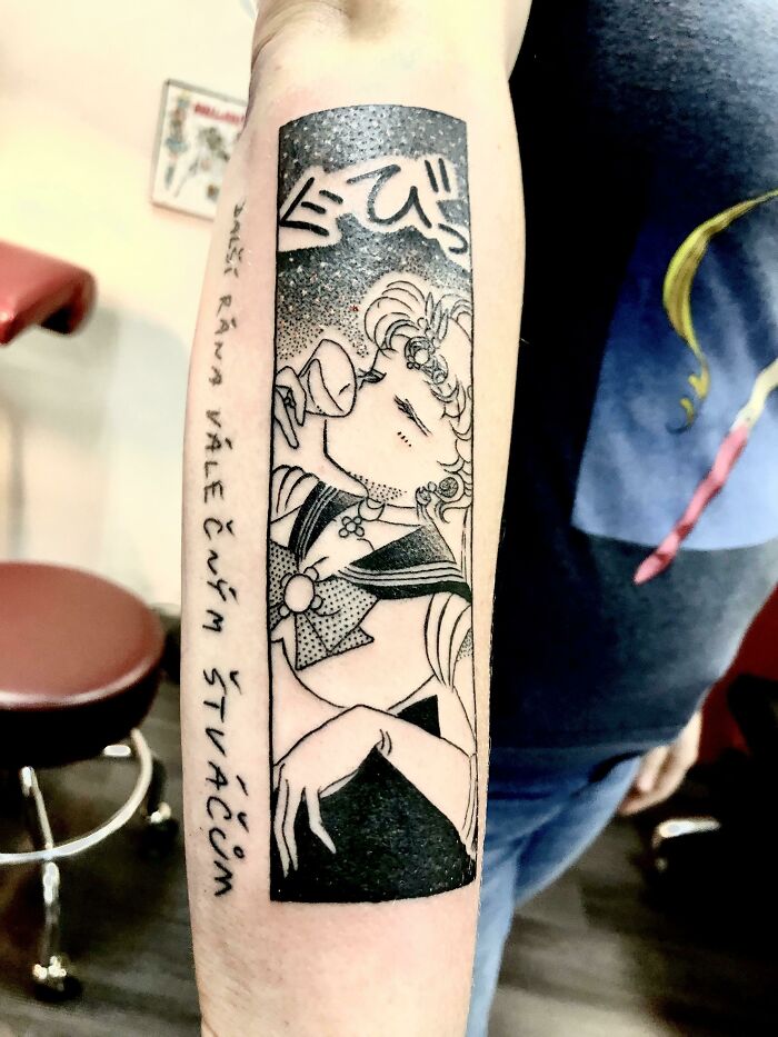 Cartoon tattoo featuring a vintage black-and-white character from Sailor Moon on a person's forearm.
