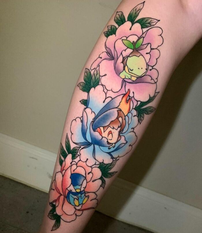 Cartoon tattoos of Pokemon characters inside colorful flowers on a forearm.