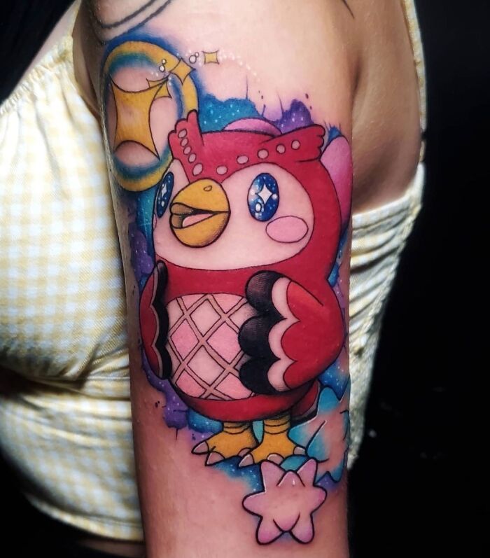 Cartoon tattoo of a colorful owl character with stars on a person's arm.
