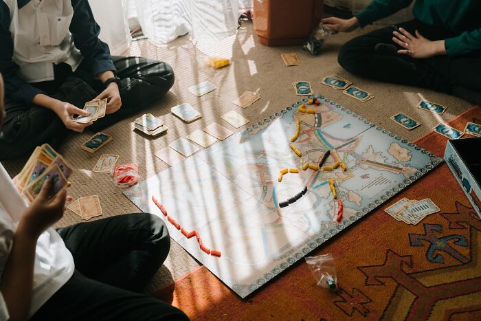 People playing a board game on New Year’s Eve, surrounded by game pieces and cards on the floor.