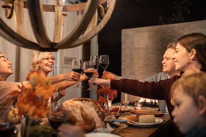 Family toasting with wine at New Year’s Eve dinner, surrounded by festive decorations and food.