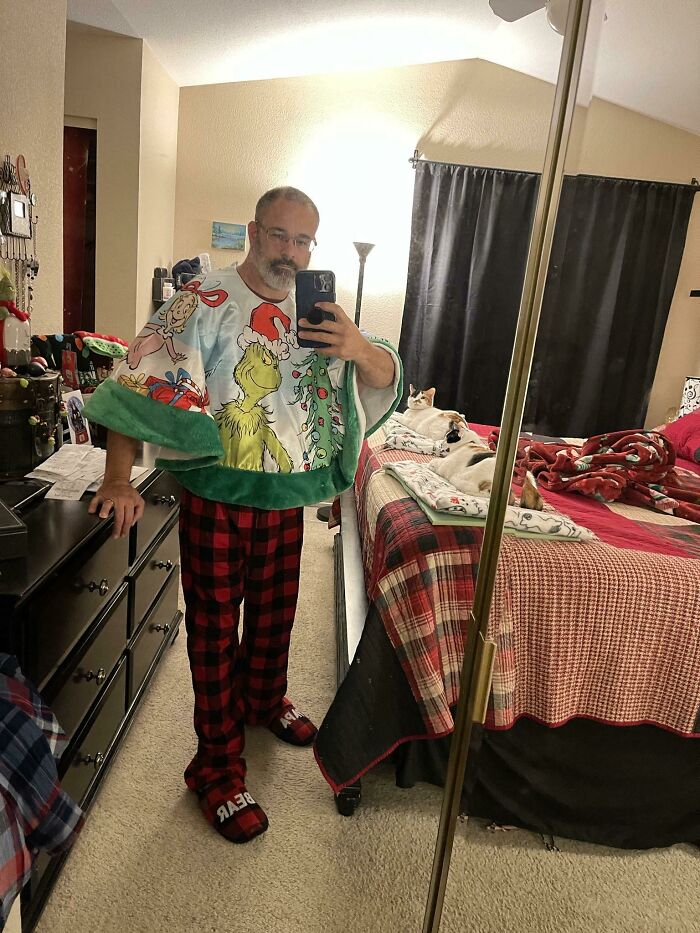 Man in a Grinch-themed towel and festive pajamas, capturing a humorous Christmas selfie.