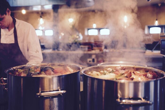 Chef preparing dishes with steaming pots, showcasing cool things to do on New Year’s Eve.