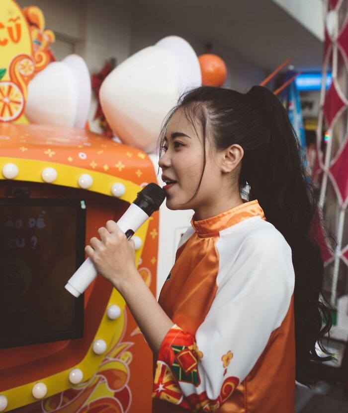 A person singing karaoke, holding a microphone, in a festive New Year’s Eve setting with colorful decorations.