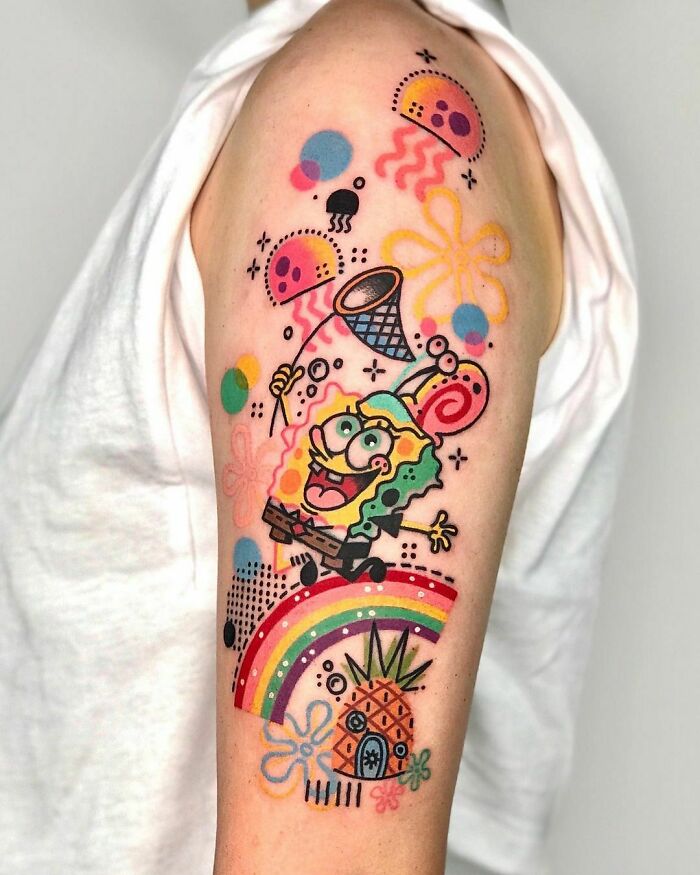 Colorful cartoon tattoo featuring a cheerful Spongebob Squarepants and rainbow on an arm, showcasing nostalgic tattoo art style.