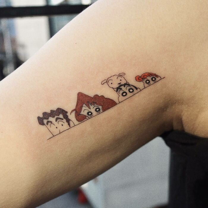 Cartoon tattoos featuring nostalgic characters on an arm, showcasing pop culture art.
