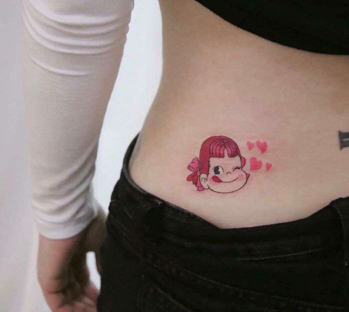 Cartoon tattoo of a smiling character with hearts on side body, inspired by favorite animated shows.