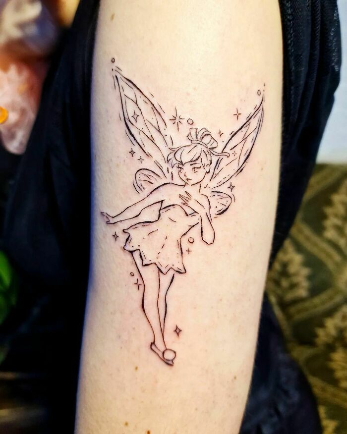 Tinkerbell tattoo on arm, capturing nostalgic cartoon vibes with delicate line art and whimsical design.