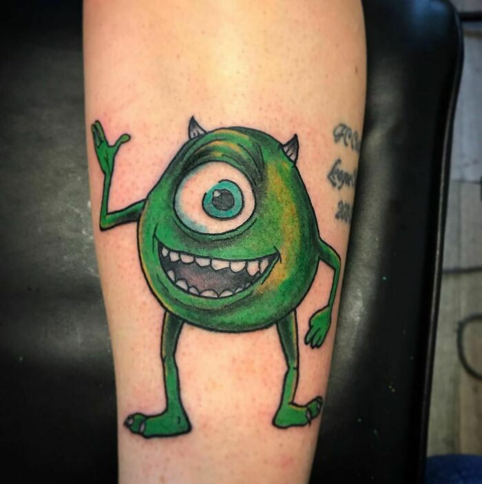 Cartoon tattoo depicting a cheerful green character with one eye, reminiscent of childhood favorites.