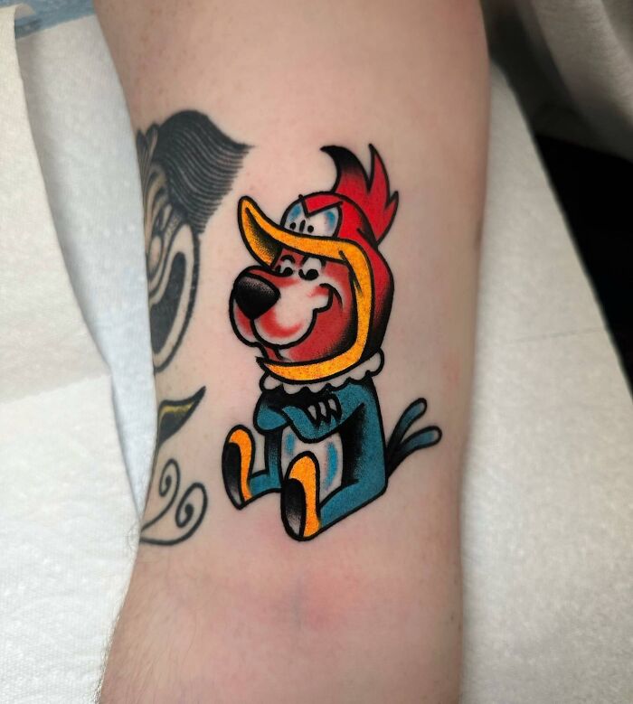 Cartoon tattoo featuring a colorful vintage character on an arm, showcasing childhood nostalgia.