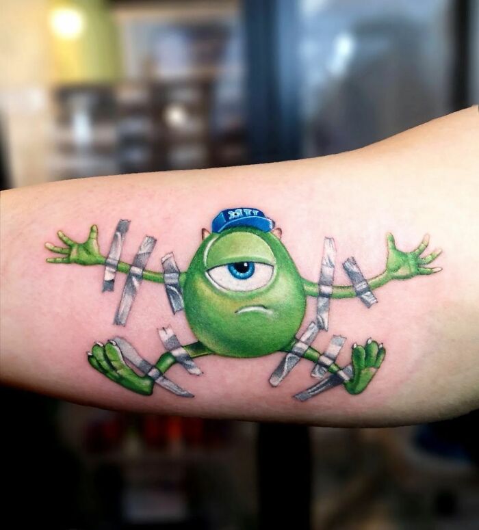 Cartoon nostalgia tattoo of Mike Wazowski taped to the skin.