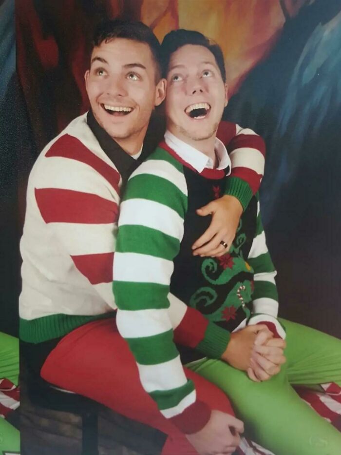 Two people in festive striped sweaters posing humorously for a Christmas photo, capturing a fun holiday moment.