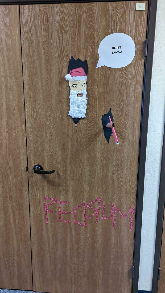 Humorous Christmas-themed door with cutouts of Santa mimicking a famous movie scene, bringing holiday humor.