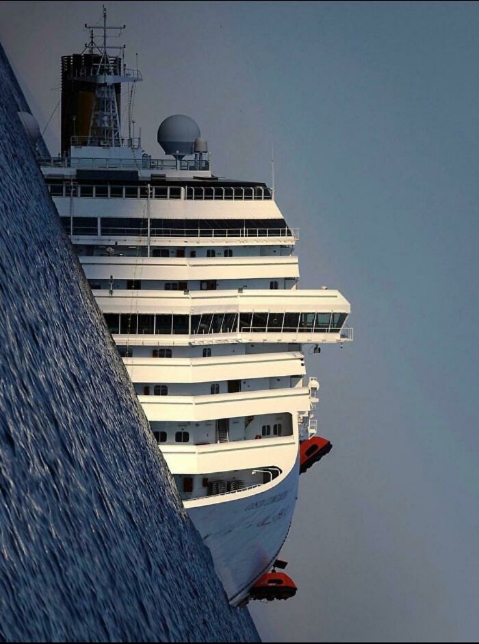 Large cruise ship tilted dramatically in the ocean, creating a frightening scene near the water surface.