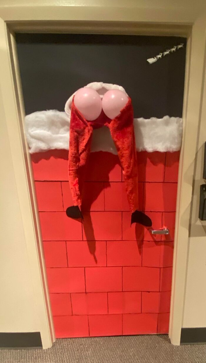 Santa decor on a door, humorously stuck in a chimney, spreading Christmas amusement.