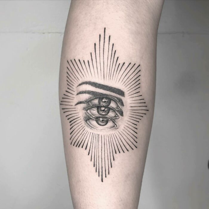 Trippy tattoo of blurred eyes with eyebrows on an arm, featuring radiating lines for a surreal effect.