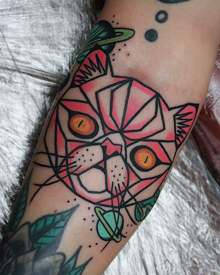 Trippy tattoo of a geometric cat face with vibrant colors and abstract design, featuring cosmic elements.