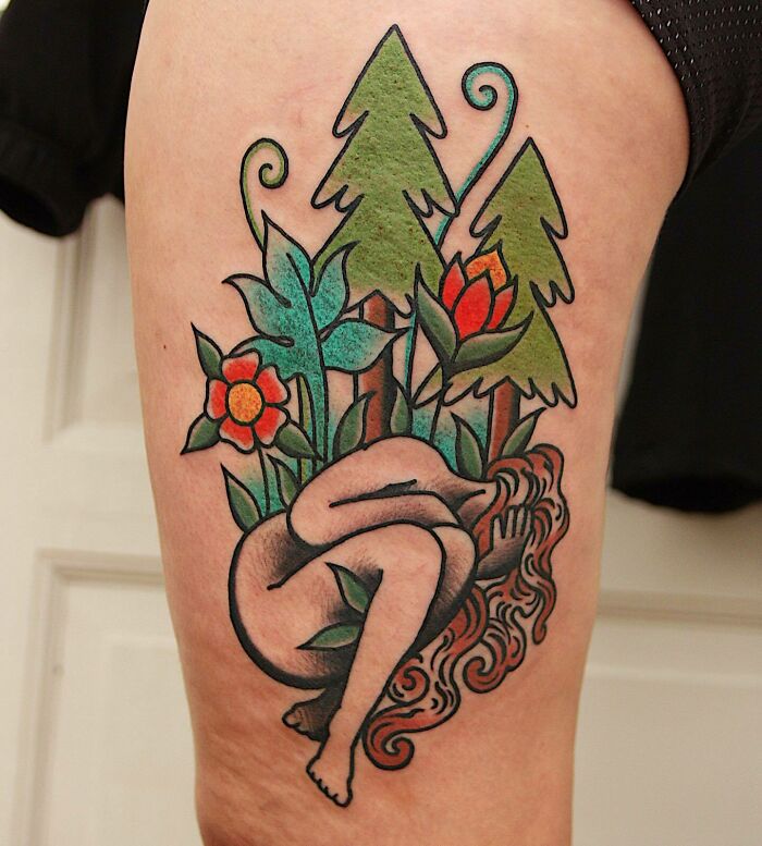 Trippy tattoo of flowers and trees on woman's leg, featuring vibrant colors and abstract design.