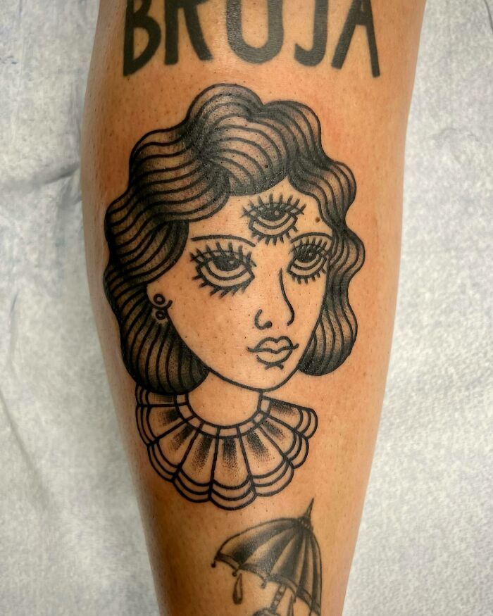 Trippy tattoo of a three-eyed woman with wavy hair and a collar on a forearm.