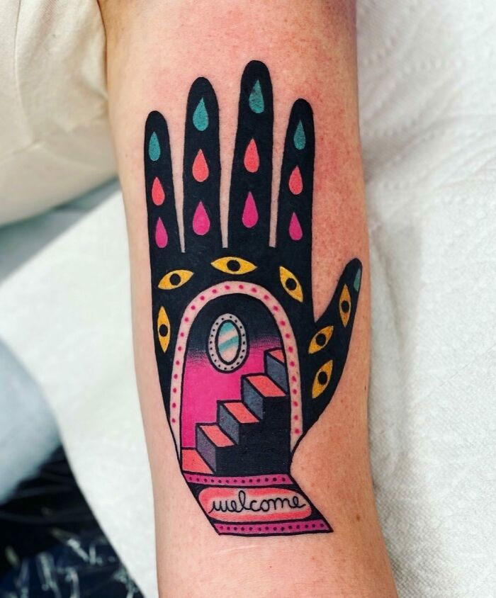 Trippy tattoo of a hand with eyes, colorful drops, and a staircase in surreal design on forearm.