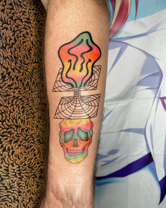 Trippy tattoo on arm depicting a colorful dimensional skull with abstract shapes.