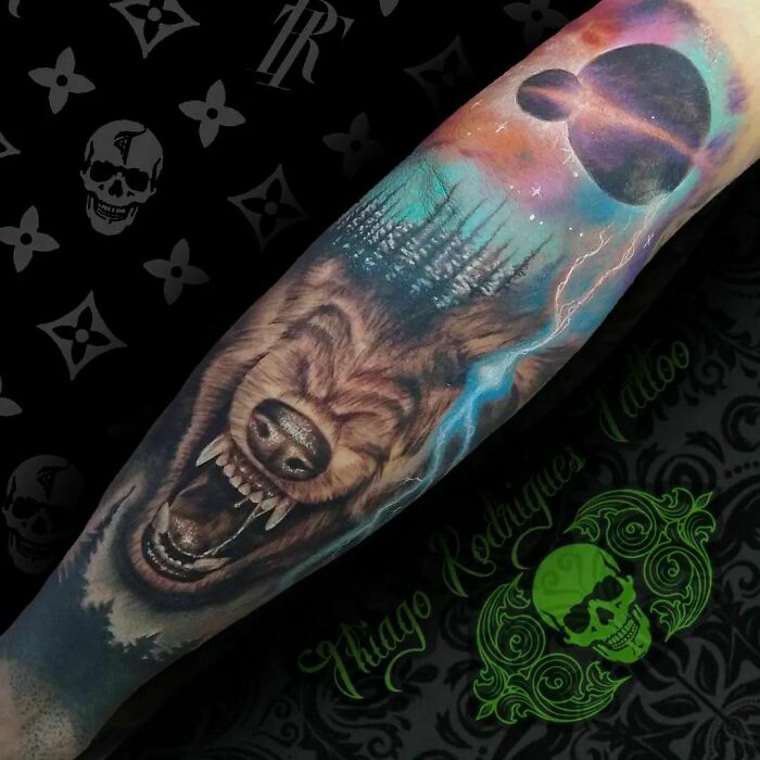 Trippy tattoo of a wolf with space and forest design on an arm.