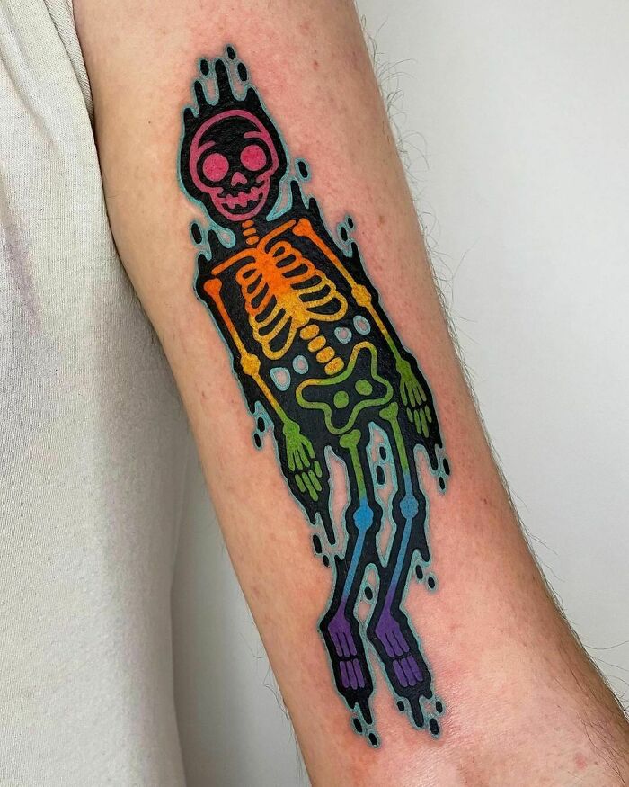 Psychedelic art tattoo of a colorful skeleton on an arm, featuring vibrant rainbow hues and a trippy design.