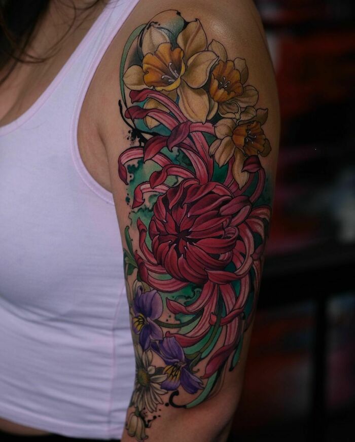 Colorful trippy tattoo with floral patterns on a woman's upper arm.