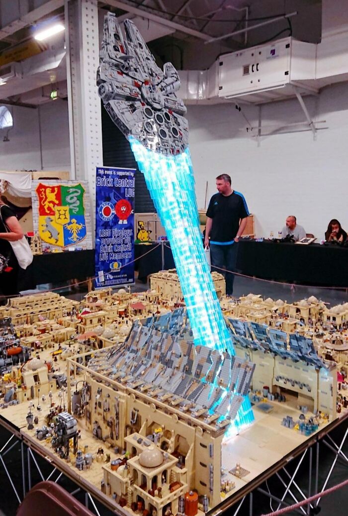 Incredible LEGO build of a spaceship launching with blue light beams over a detailed desert village model display.
