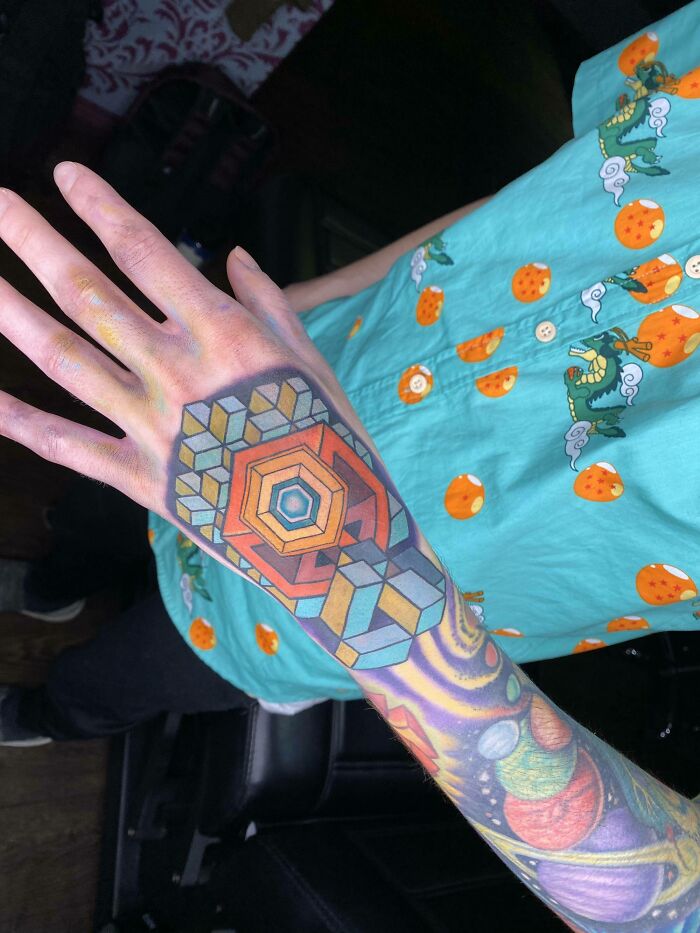 Colorful trippy tattoo with geometric design and vibrant patterns on an arm.