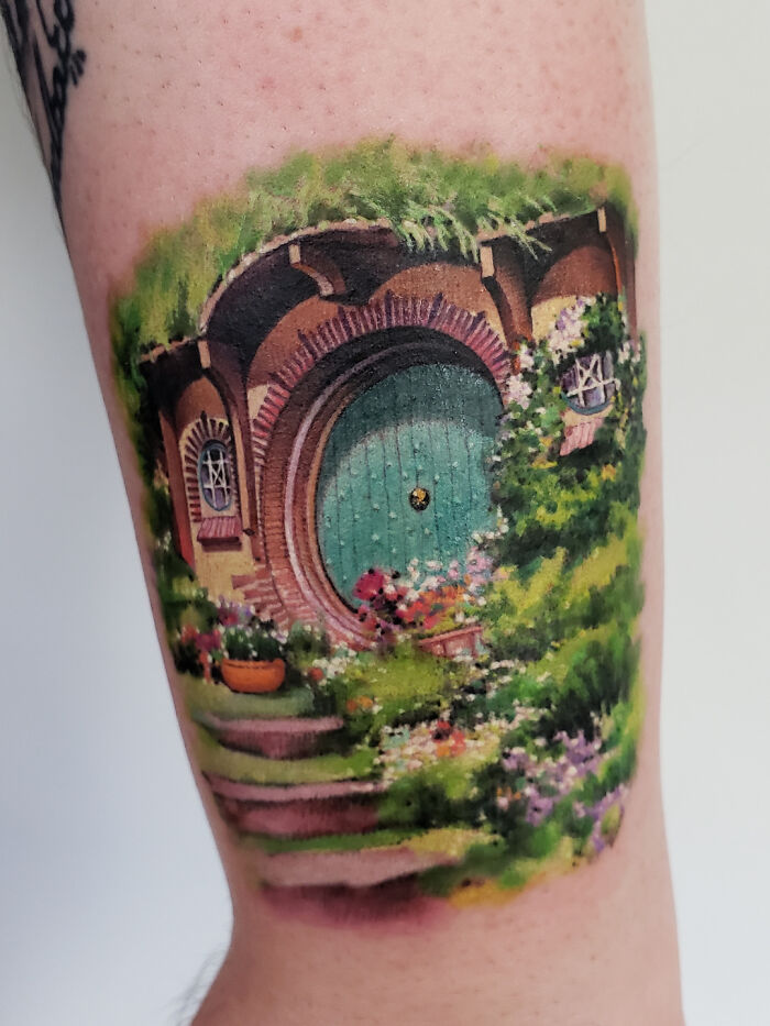 Psychedelic art tattoo of a colorful, detailed Hobbit-inspired house on skin.