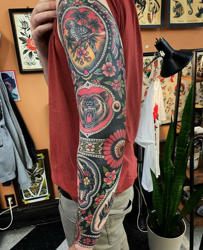 Colorful trippy animal and flowers arm sleeve tattoo in a tattoo studio setting.